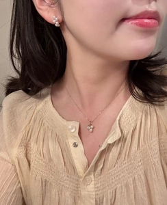 Close-up of elegant gold pearl necklace set with three-petal zircon flower on a model
