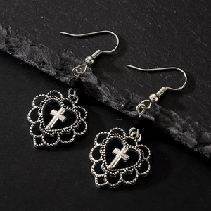 Detail view of silver gothic earrings with hollow heart and cross charm on black rock