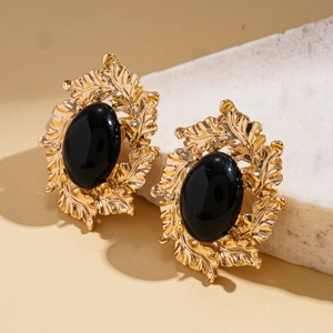 Close-up of vintage baroque gold leaf earrings with oval black resin center inlay