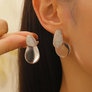 Detailed close-up of water drop earrings with gold base and clear resin pendant