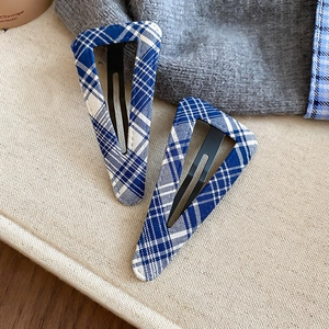 Detail shot of two blue and white plaid fabric triangle hair clips with black BB base