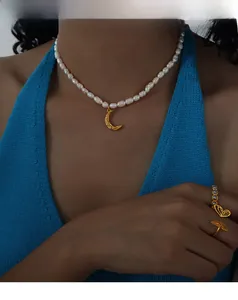 Detail of freshwater pearl necklace with crescent pendant and gold butterfly ring