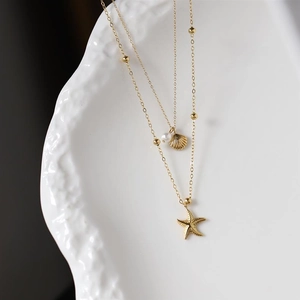 Detail einer zweilagigen Goldkette mit Seestern-, Muschel- und Perlenanhängern