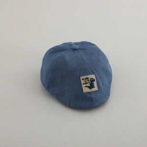 Dettaglio del berretto piatto in denim blu per bambini con toppa a dinosauro