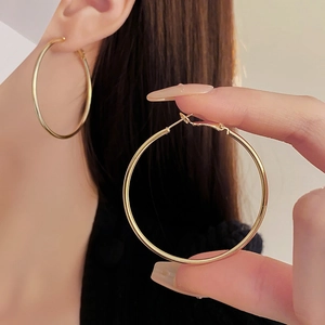 Close-up of elegant large golden circular hoop earrings worn by a model