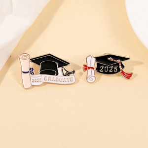 Detailed view of 2025 graduation pins with mortarboard and scroll in enamel finish