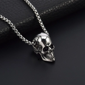 Macro shot of silver hip hop skull pendant and stainless steel box chain on leather
