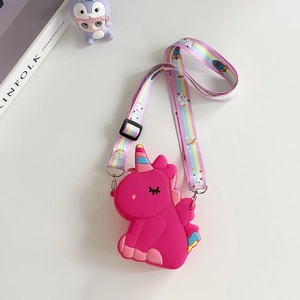 Detail of a bright rose pink unicorn silicone crossbody bag with rainbow strap on a desk