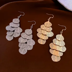 Elegant gold and silver irregular tiered leaf tassel earrings on dark brown velvet background