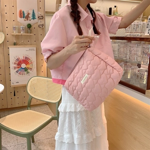 Detail of pink quilted heart pouch showing soft padded texture and side brand label