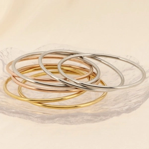 Detailed view of stacked 18k gold silver and rose gold polished bangle bracelets