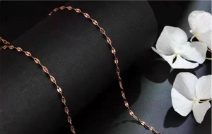 Dettaglio della collana a catena in oro rosa su un supporto cilindrico nero minimalista