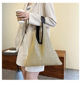 Close-up of woven straw tote bag with black leather handle detail on a model outfit