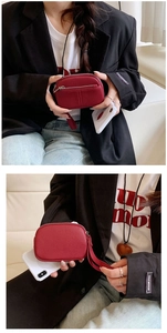 Detailed close-up of a red textured leather mini wallet with silver zipper and wrist strap
