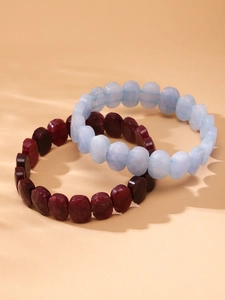 Détail de bracelets en pierres naturelles bleu clair et bordeaux sous une lumière douce