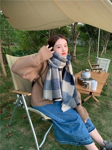 Close-up of blue plaid scarf with fringes worn by a model in an outdoor camping setting