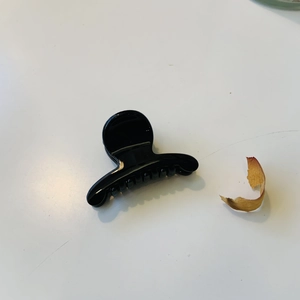 Détail d'une pince à cheveux en plastique noir brillant avec dents imbriquées sur fond blanc