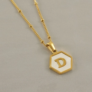 Detailed macro shot of a hexagonal 18k gold-plated pendant with a white inlay and D letter
