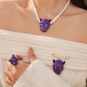 Gros plan détaillé de l'ensemble bijoux tête de léopard violet avec collier et broche