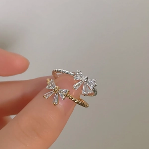 Detailed view of silver and gold bow rings with shimmering cubic zirconia stones