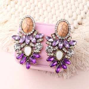Elegant floral bohemian dangle earrings with purple and white crystals on pink velvet