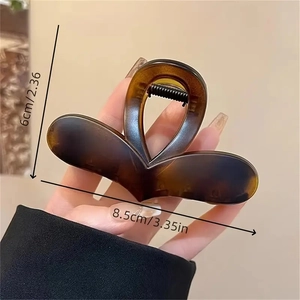 Elegant heart-shaped amber hair claw clip shown in hand with size dimensions 8.5x6cm