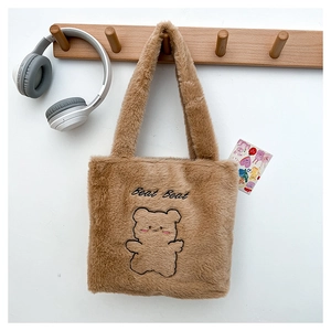 Détail du cabas en peluche marron avec broderie ours et texture douce sur un support mural