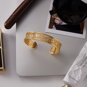 Elegant gold-tone titanium steel open cuff bracelet featuring an intricate hollow pattern