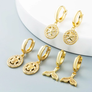 Detailed view of three gold hoop earrings featuring starfish, turtle and whale tail charms