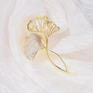 Detailaufnahme einer goldenen Ginkgoblatt-Brosche mit Ausschnitten und Pavé-Diamanten