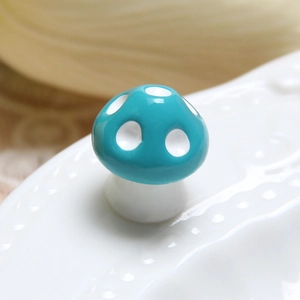 Macro shot of 14mm ceramic forest mushroom miniature with teal cap and white spots