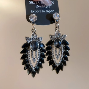 Dettaglio macro di orecchini a fiore vintage in argento con pietra blu e cristalli
