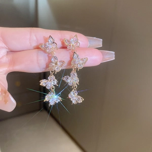Close-up of dangling gold butterfly earrings with sparkling cubic zirconia crystals