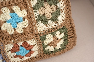 Detailed close-up of multi-color granny square crochet pattern on woven straw tote bag