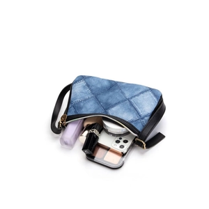 Blue denim texture underarm bag with black leather trim and gold zippers on white background
