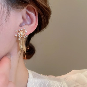 Detail of starburst fringe earrings with white pearls and sparkling zircons for women