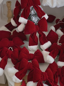 Close-up of red velvet Christmas bows with faux fur trim and white hanging strings