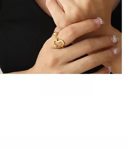 Detalle de un anillo abierto dorado con diseño ondulado y puntas esféricas