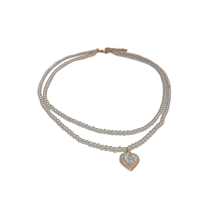 Double-layer pearl necklace with heart pendant and gold clasp on white background