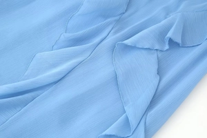 Macro shot of blue chiffon fabric with delicate pleated ruffles and layered textures