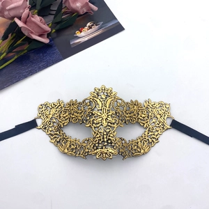Macro shot of gold lace embroidery mask with intricate metallic thread detail and black ties
