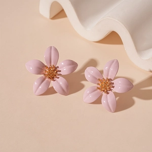 Close-up of pink flower stud earrings with golden center on a minimal background