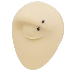 Close-up of black double-ball eyebrow ring on skin-tone silicone practice piercing model