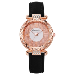 Close-up of rose gold quartz watch with rhinestone bezel and black leather strap