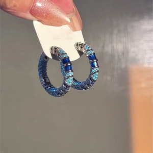 Macro detail of vintage-style hoop earrings featuring blue and turquoise stone inlays