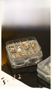 Close-up of clear two-layer acrylic jewelry box showing multi-grid interior storage