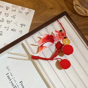 Detailed macro view of Chinese-style gold fish embroidery hairpin with red tassel