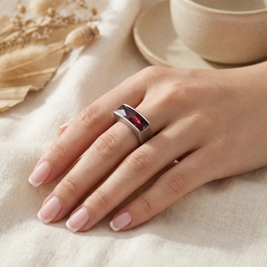 Detail view of a rectangle dark red stone set on a wide matte silver stainless steel ring