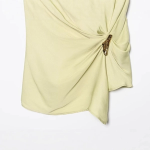 Chic off-shoulder asymmetric top in light yellow pleated fabric with gold buckle detail