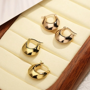 Detailed macro view of U-shaped gold and rose gold hoop earrings in a jewelry box
